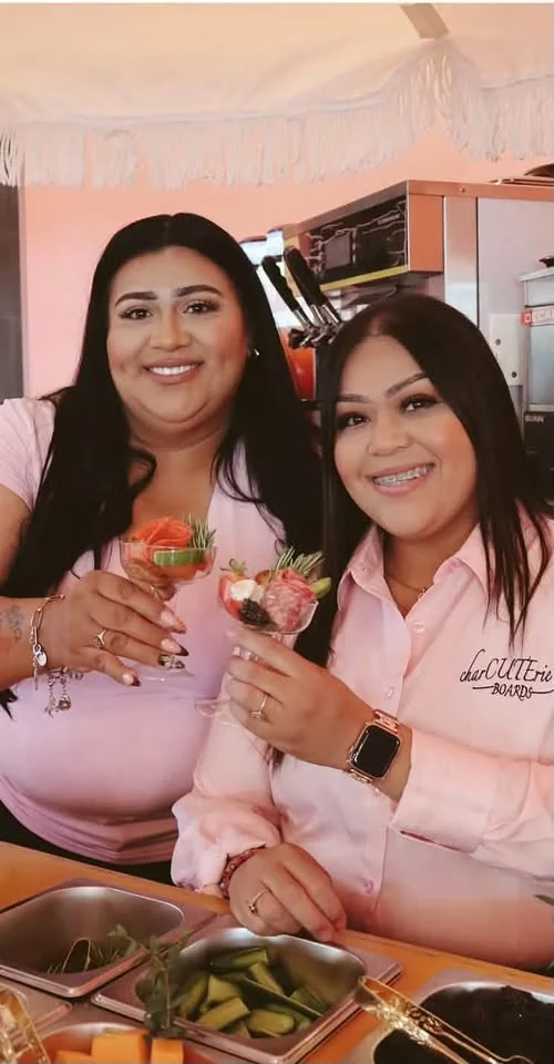 Gloria and a collaborator smiling at a charcuterie event