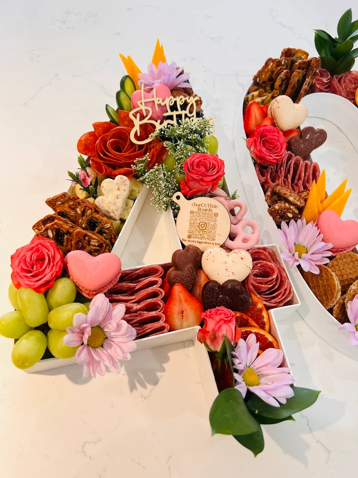A custom birthday charcuterie board with fruit, flowers, cheese, and celebratory details