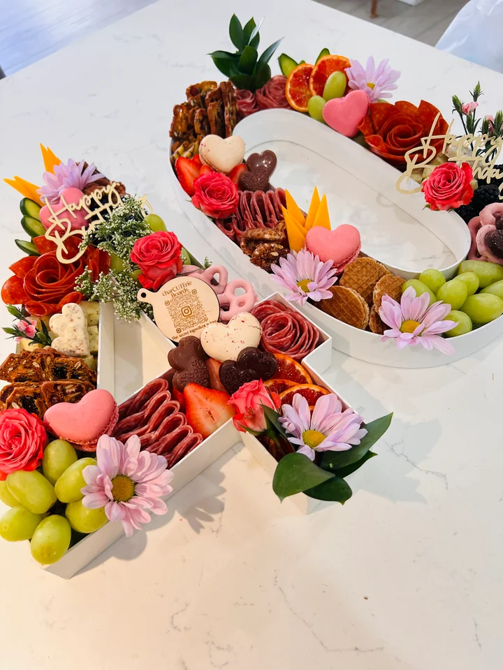 Two custom birthday boards with flowers and celebratory toppers