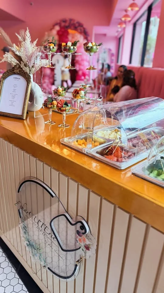 Charcuterie station arranged along a pink event venue bar