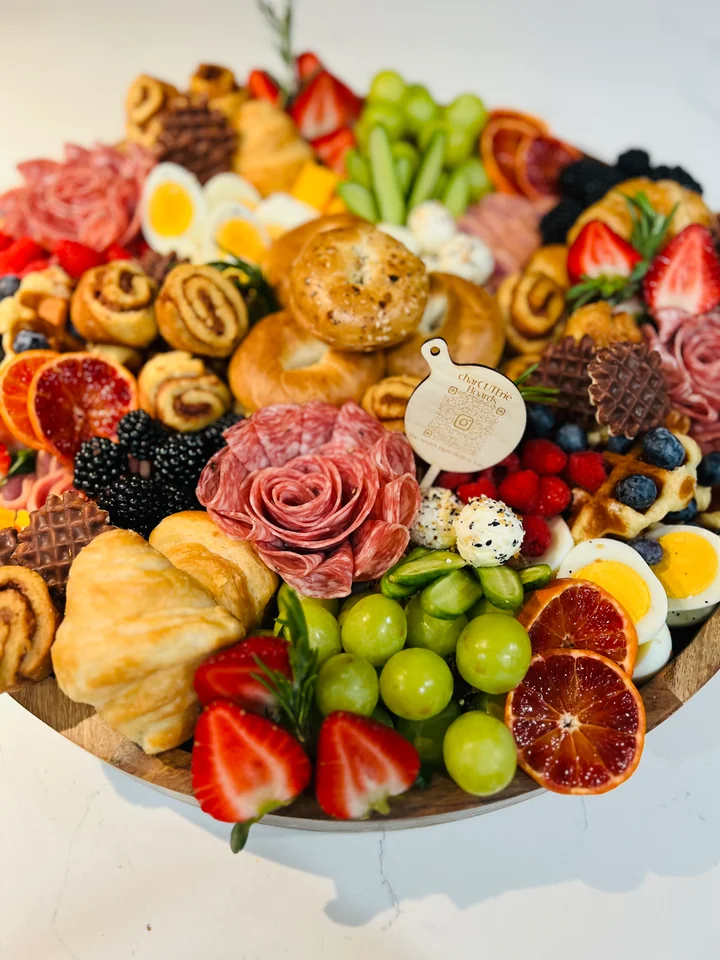 Round celebration charcuterie board with fruit, cheese, and croissants